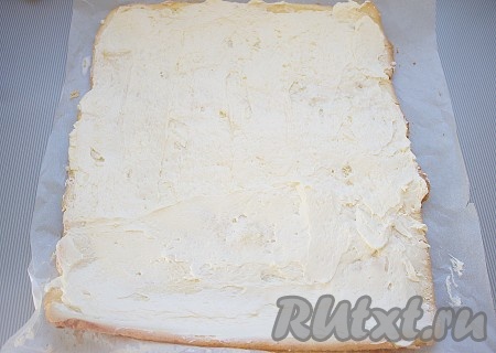 Затем рулет аккуратно развернуть, освободить от пергамента (переложить на чистый пергамент), сбрызнуть пропиткой (сгущенку растворить в кипятке), всю поверхность смазать 2/3 крема. 
