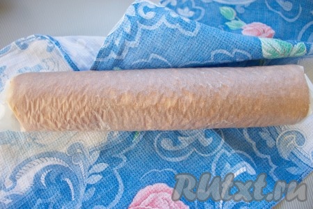 Готовый бисквит достать и сразу вместе с пергаментом свернуть в рулет, завернуть в полотенце и дать немного остыть.
