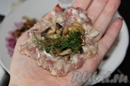 Из части фарша формируем лепёшку. В центр лепешки кладём немного жареных грибов и, по желанию, веточку укропа (как на фото), поднимаем края мясной лепёшки вверх и защипываем, формируя котлету. Таким образом формируем все мясные котлеты с грибами внутри.