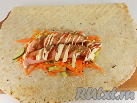 Смазать сосиски сверху кетчупом, майонезом и горчицей по вкусу.