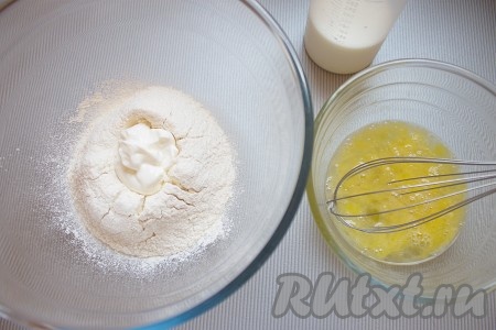 Для приготовления блинчиков в миску просеять муку и разрыхлитель. Затем в серединке муки сделать углубление, добавить сметану, теплое молоко и слегка взбитые яйца с солью.
