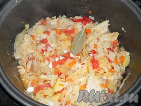 Также добавить нашинкованную капусту, предварительно посоленную и помятую руками. Посыпать паприкой и специями. Выставить режим "Тушение" на 30 минут. За 10 минут до окончания готовки добавить лавровый лист и порезанный мелкими кусочками чеснок.
