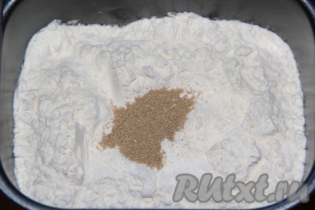 Всыпать кукурузную и пшеничную муку. В серединку добавить дрожжи, а в углу ведёрка разместить соль.
