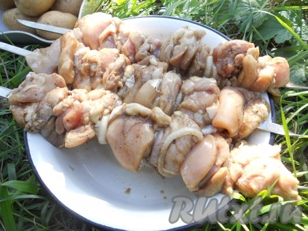 Нанизать кусочки курицы на шампуры вместе с кольцами лука.