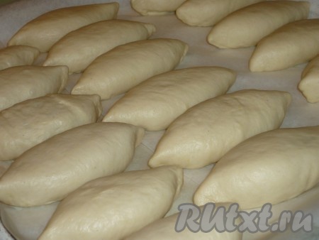 Постепенно формируем все 18 пирожков с зелёным луком, рисом и яйцом, выкладываем их швом вниз на небольшом расстоянии друг от друга на противень, застеленный пергаментом. Оставляем пирожки на расстойку на 10-15 минут в тёплом месте. Затем ставим на 25-30 минут в духовку, разогретую до 180 градусов.