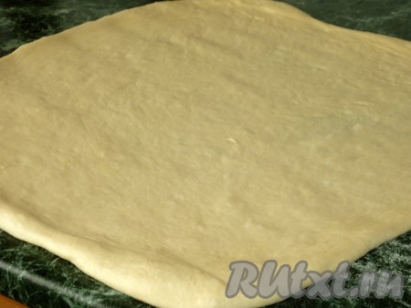 Подошедшее тесто хорошо обминаем и раскатываем на рабочей поверхности.
