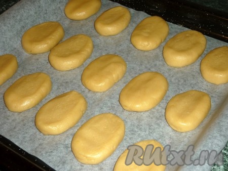 Каждому кусочку теста придаём овальную форму и выкладываем на противень, застеленный пекарской бумагой.
