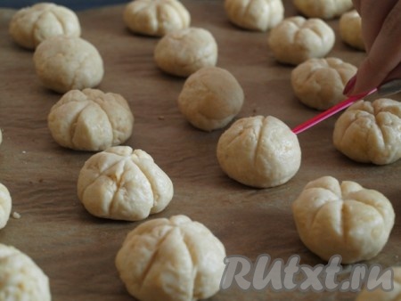 От охлажденного теста отщипывать кусочки (по размеру немного больше грецкого ореха) и формировать из них шарики. Выложить на противень, застеленный пергаментной бумагой. На каждом шарике зубочисткой или палочкой нарисовать небольшие борозды.
