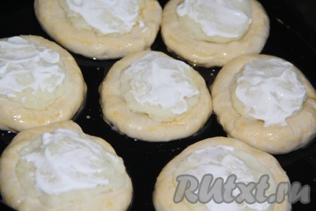 Готовые ватрушки с картошкой выложить на противень, смазанный растительным маслом. Прикрыть противень с ватрушками полотенцем или пищевой плёнкой и оставить на 30 минут для подъёма. Затем смазать тесто взбитым желтком, а поверхность пюре смазать сметаной.
