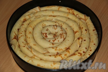 Подготовленные блинчики плотно выложить в виде улитки в круглую форму (я использовала разъёмную форму).