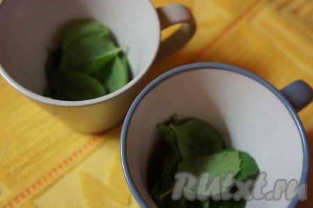 Мяту промыть водой, разделить на листики. Равномерно разложить листья мяты по 2 бокалам.