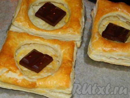 За 5 минут до окончания выпечки достаём слойки из духовки, кладём в середину по кусочку шоколада и отправляем в духовку. Достаём из духовки и размазываем вилкой мягкий шоколад по дну пирожного. Даём остыть.
