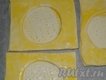 Середину (круг) накалываем вилкой. Верхний квадрат смазываем яичным желтком. Выпекаем слойки на противне, застеленном пекарской бумагой, примерно 30 минут при температуре 190 градусов до румяного цвета.
