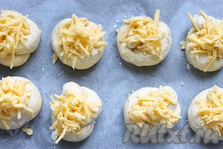 Готовые "узелки" выложить на расстоянии друг от друга на противень, застеленный пергаментом, смазать их молоком и посыпать сыром, натёртым на крупной тёрке.