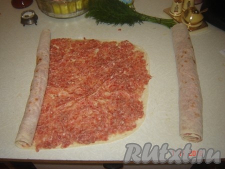 Разворачиваем лаваш, намазываем на него тонким слоем фарш и сворачиваем его рулетом, затем рулет разрезаем на равные кусочки поперёк так, чтоб кусочки были ниже борта сковороды на пару сантиметров.
