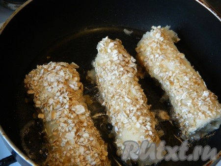 Сворачиваем каждый кусочек хлеба с сыром в рулет, обмакиваем в яйцо, затем - в овсяные хлопья. В сковороде прогреваем растительное масло, выкладываем несколько рулетиков из хлеба с сыром в яйце, обжариваем на среднем огне до подрумянивания&nbsp;со всех сторон.