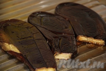 Запекаем овощи примерно 40 минут (и баклажаны, и перцы должны стать достаточно мягкими, легко прокалываться вилкой). Достаём запечённые овощи из духовки. Горячие перцы кладём в целлофановый пакет, завязываем (это нужно для того, чтобы в дальнейшем было легче снимать шкурку), даём остыть. Горячие баклажаны ставим под гнёт (то есть поверх баклажанов выкладываем разделочную доску, а на неё ставим небольшую банку с водой). Гнёт нужен для того, чтобы из баклажанов вышла лишняя жидкость, а с ней и горечь.