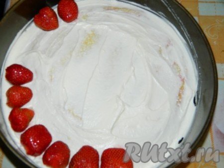 Корж достаём из духовки, даём остыть. Остывший корж я выложила на тарелку и поставила бока от формы. Пропитываем корж яблочным соком. Выкладываем немного творожно-сливочного крема, затем раскладываем целые ягоды клубники.
