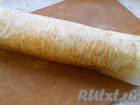 Горячий корж свернуть в рулет с помощью пергамента и оставить в таком положении, пока полностью не остынет.