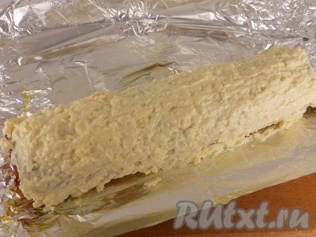 Достать рулет из холодильника, фольгу развернуть и покрыть сырной массой рулет сверху и по бокам с помощью ножа. Снова отправить рулет в холодильник на 30 минут, фольгу не сворачивать.