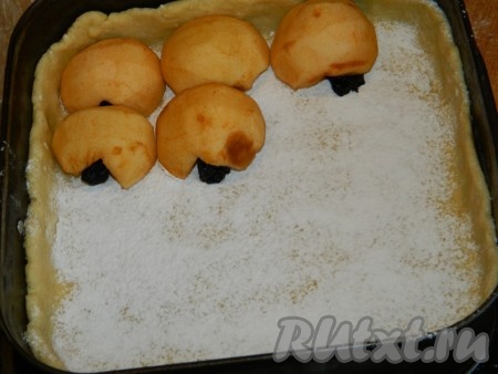 Половину теста раскатываем и выкладываем в форму, формируя бортики. Посыпаем крахмалом. Выкладываем на тесто половинки яблок, пряча под каждую половинку яблочка по одному черносливу.