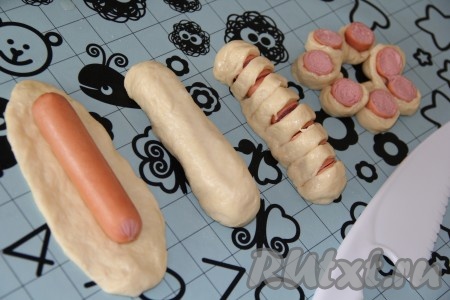 Разделить тесто на небольшие части. Из каждой части теста раскатать овал, положить сосиску на середину теста. Завернуть сосиску в тесто и хорошо закрепить края. Сделать 7 надрезов, не дорезая тесто до конца. Сформировать сосиску в тесте&nbsp; в виде цветочка.
