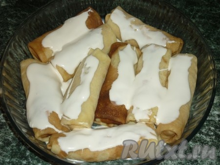 Блинчики перекладываем в форму для выпечки, сверху поливаем сметаной.
