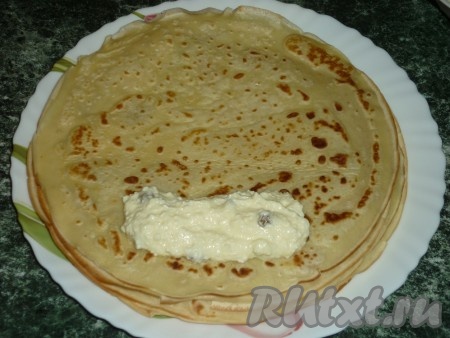 На край блина кладём начинку из творога и изюма.