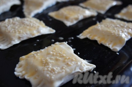 Противень смазать растительным маслом (или застелить пергаментом), выложить слойки с сыром. В небольшой ёмкости сырое яйцо взболтать вилкой до однородности. Смазать взбитым яйцом каждую слойку с сыром. Сверху, по желанию, посыпать кунжутом и поставить в духовку, разогретую до 180 градусов, на 20 минут (до подрумянивания слоёного бездрожжевого теста).