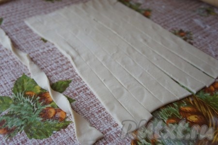 Тесто для этой выпечки можно взять как дрожжевое, так и бездрожжевое. У меня тесто было в 2 пластах. Для формирования палочек я взяла 1 пласт слоёного теста. Разморозить тесто, оно должно стать достаточно мягким. На присыпанной мукой поверхности раскатать слоёное тесто до толщины примерно 3 миллиметра, затем нарезать на полоски шириной 1 сантиметр (у меня получилось 9 полосок). По желанию можете их ещё и закрутить, как показано на фото.