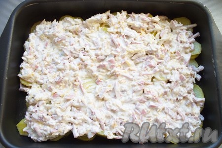 Через 30-35 минут достать картофель, выложить на него подготовленную "шубу" ровным слоем и снова поставить в духовку на 15-20 минут, запекать до чуть золотистого цвета.