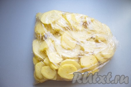 Картофель очистить и нарезать кружочками толщиной примерно 3 мм, чеснок очистить и мелко порезать. Овощи положить в полиэтиленовый пакет, добавить растительное масло, соль, перец красный и черный, розмарин. Пакет плотно завязать и хорошенько встряхнуть, чтобы весь картофель покрылся специями и маслом. Оставить на несколько минут и снова потрясти.