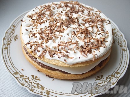 Накрыть вторым бисквитом, его смазать остатками сливок, посыпать тертым шоколадом.