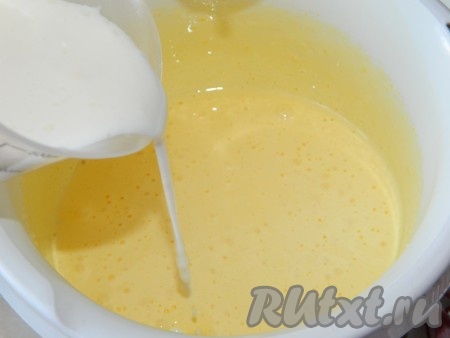 Прежде всего замесим тесто для бисквита. Для этого кефир нужно смешать с содой в глубокой миске и оставить минут на 5 (на время, пока будем взбивать яйца), постепенно сода погасится в кефира, поэтому смесь немного увеличится в объёме, на поверхности появятся пузырьки. Пока сода гасится в кефире, нужно в чашу для взбивания миксером выложить яйца и сахар, взбить миксером в течение 5 минут. Масса увеличится в объёме и побелеет. Добавить ко взбитой массе кефир, смешанный с содой, перемешать миксером на небольших оборотах.