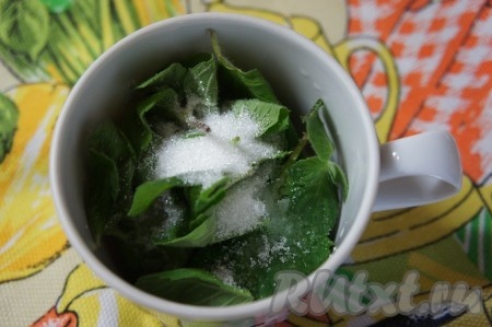 Веточки мяты вымыть, отделить листочки (веточки нам не понадобятся). Листья мяты немного обсушить, выложить в глубокую чашку, засыпать 1 чайной ложкой сахара.