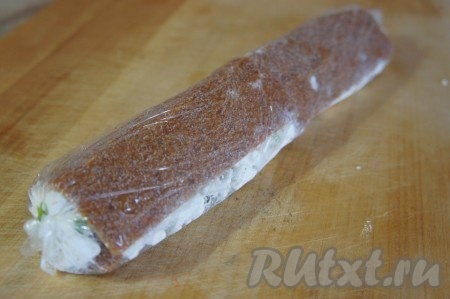 Пласт из хлебцев с творогом, помогая себе пищевой плёнкой, свернуть в плотный рулет. Затем завернуть получившийся рулет в пищевую плёнку и поместить минут на 30 в холодильник.