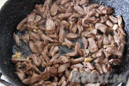На сковороде разогреть растительное масло и выложить куриные сердечки, обжаривать их, периодически перемешивая, 10 минут на среднем огне.