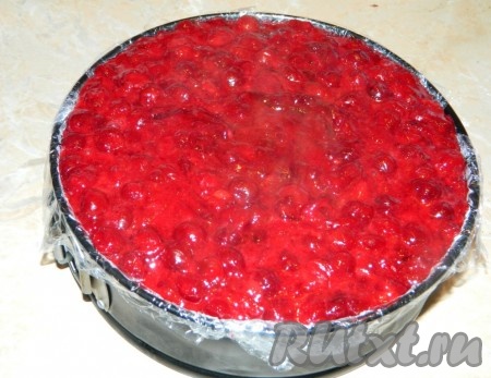 Вишневый слой выложить на торт горячим, разровнять и снова поставить в холод. Приготовленный застывший торт освободить от пленки. Бока торта я украсила тёртым шоколадом и переложила на тарелку. 