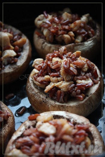 Сок, образовавшийся в шляпках при запекании, не выливаем, выкладываем начинку из курицы и риса, отправляем снова на 25-40 минут в духовку (время запекания зависит от размера шампиньонов).
