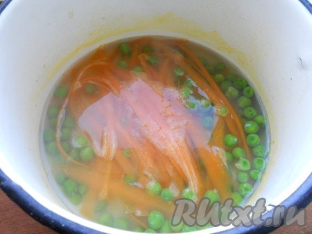 Воду вскипятить, всыпать горошек. Варить на слабом огне 5 минут. После этого добавить в кастрюльку с горошком морковь, порезанную с помощью овощечистки длинными, тонкими пластинами. Продолжать варить еще 3-4 минуты. Затем морковь с горошком откинуть на дуршлаг и промыть холодной водой.
