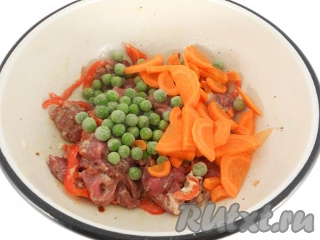 К говядине и болгарскому перцу добавить сметану, влить растительное масло, хорошо перемешать. Добавить зелёный горошек (замороженный горошек размораживать не нужно) и морковь, нарезанную на тонкие полукружочки.