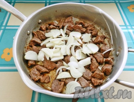 Нарезать весь лук, половину выложить к мясу, перемешать. Обжарить все вместе, чтобы лук зарумянился. Влить немного горячей воды, чтобы покрыла мясо на половину, уменьшить огонь и готовить мясо под крышкой до готовности, в течение 1 часа.
