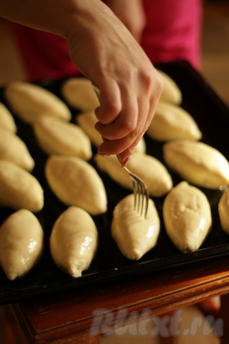 Таким образом сформировать все пирожки, выкладывая их на противень, смазанный растительным маслом. Выкладывать пирожки нужно на небольшом расстоянии друг от друга. Оставить пирожки на противне минут на 20 (пирожки за этой время немного увеличатся в объёме). Затем наколоть каждый пирожок вилкой. В небольшой ёмкости вилкой взбить желтки, получившейся желтковой смесью смазать все пирожки.