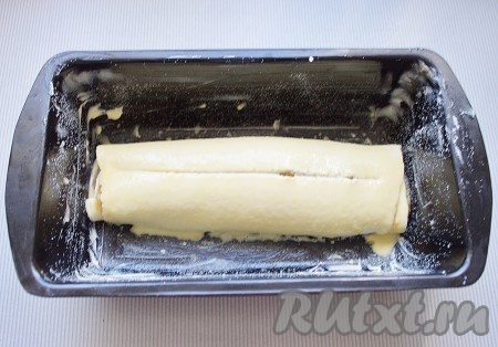 Рулет уложить в форму для выпечки (у меня прямоугольная для кекса размером 13х23 см), смазанную сливочным маслом и присыпанную панировочными сухарями.&nbsp;Рулет смазать смесью желтка и апельсинового сока, по середине сделать неглубокий надрез (при выпечке воздух будет выходить из рулета и слои будут плотными и красивыми, без полостей).
