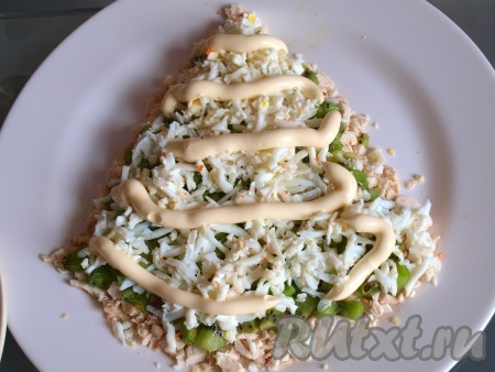 Разделяем яйца на белки и желтки. В майонез добавляем чеснок, пропущенный через пресс, и перемешиваем. На слой киви выкладываем натёртые белки, смазываем майонезом.
