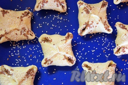 Духовку разогреть до 200 градусов. Яйцо взбить вилкой, смазать слойки яйцом, посыпать кунжутом и семенами льна.
