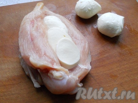 Шарики моцареллы порезать кружочками и поместить в середину куриного филе. Посыпать немного итальянскими травками и солью.
