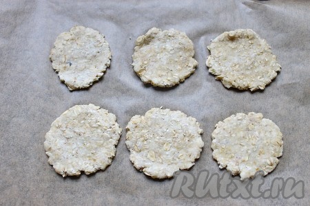 Каждую часть теста скатать в круглую лепёшку. Лепёшки выложить на противень, застеленный пергаментом, на небольшом расстоянии друг от друга и ладонью приплюснуть так, чтобы получилась тонкая, круглая лепёшка. Поверхность овсяных лепёшек смазать желтком.