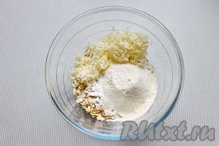 Сливочное масло для приготовления лепёшек должно быть комнатной температуры, поэтому заранее достаньте его из холодильника, чтобы оно согрелось и стало мягким. В миске соединить овсяные хлопья, просеянную муку, разрыхлитель, сыр и соль, перемешать.