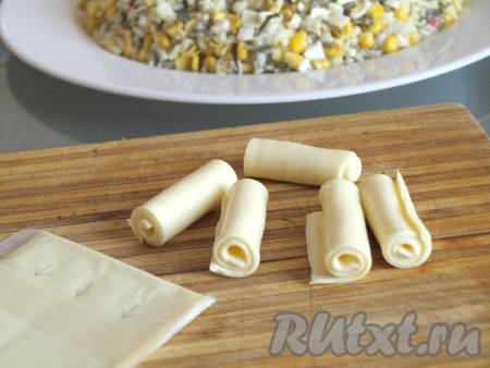 Для оформления свечей используем бутербродный плавленый сыр. Скатываем каждую пластину в трубочку и разрезаем пополам.
